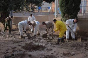 Several people in yellow jackets are digging in the dirt as part of storm damage restoration efforts.