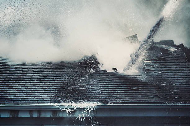A fireman sprays water on a roof during a fire and water restoration effort.