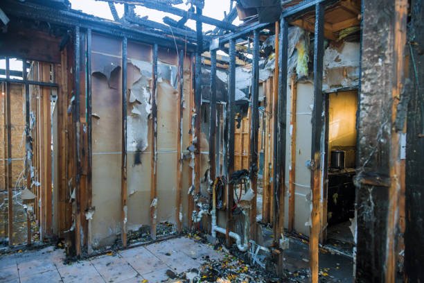 A charred room featuring a door and a window, with blackened walls and debris scattered across the floor—an urgent scene requiring professional Fire Damage Restoration