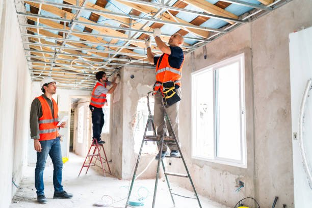 Construction workers repairing a house with visible ceiling water damage during the building process.