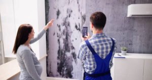  A man and woman stand before a moldy wall, highlighting the need for water damage restoration services.