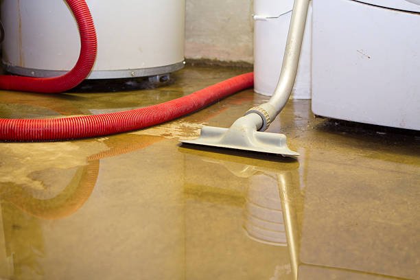 A flooded room features a white washing machine and a hose, highlighting the need for basement clean-up efforts.