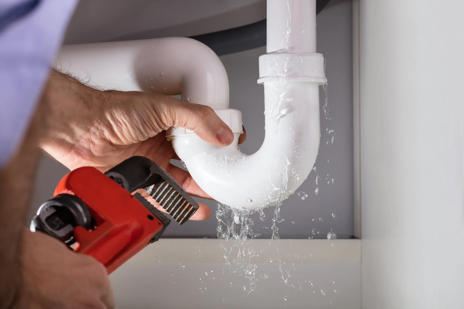 A man repairs a pipe using a tool, focusing on plumbing leak detection.