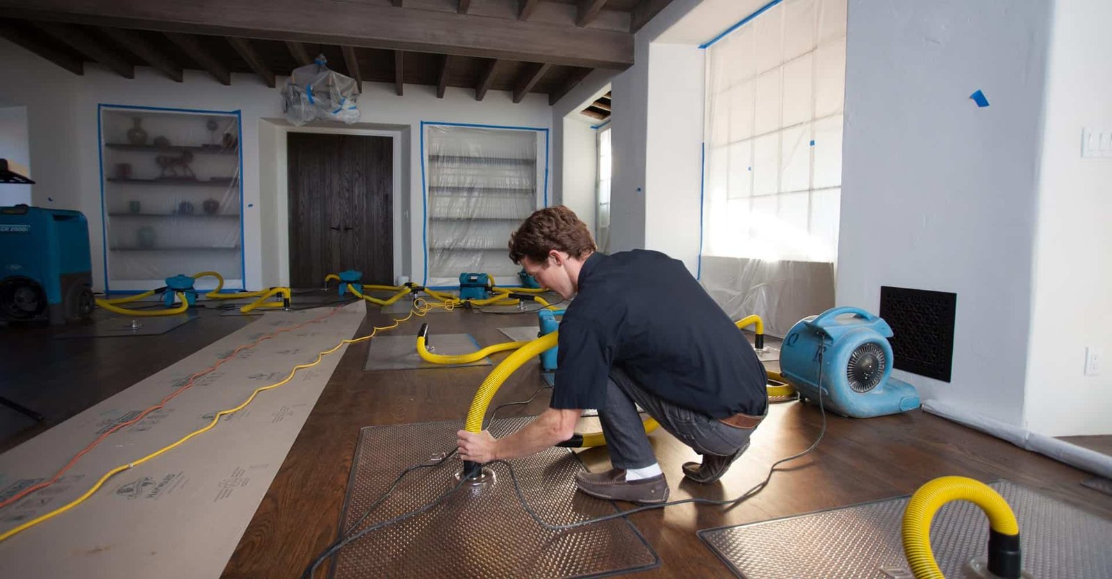 Professional water damage restoration equipment and extraction hoses deployed in a heavily flooded building hallway.
