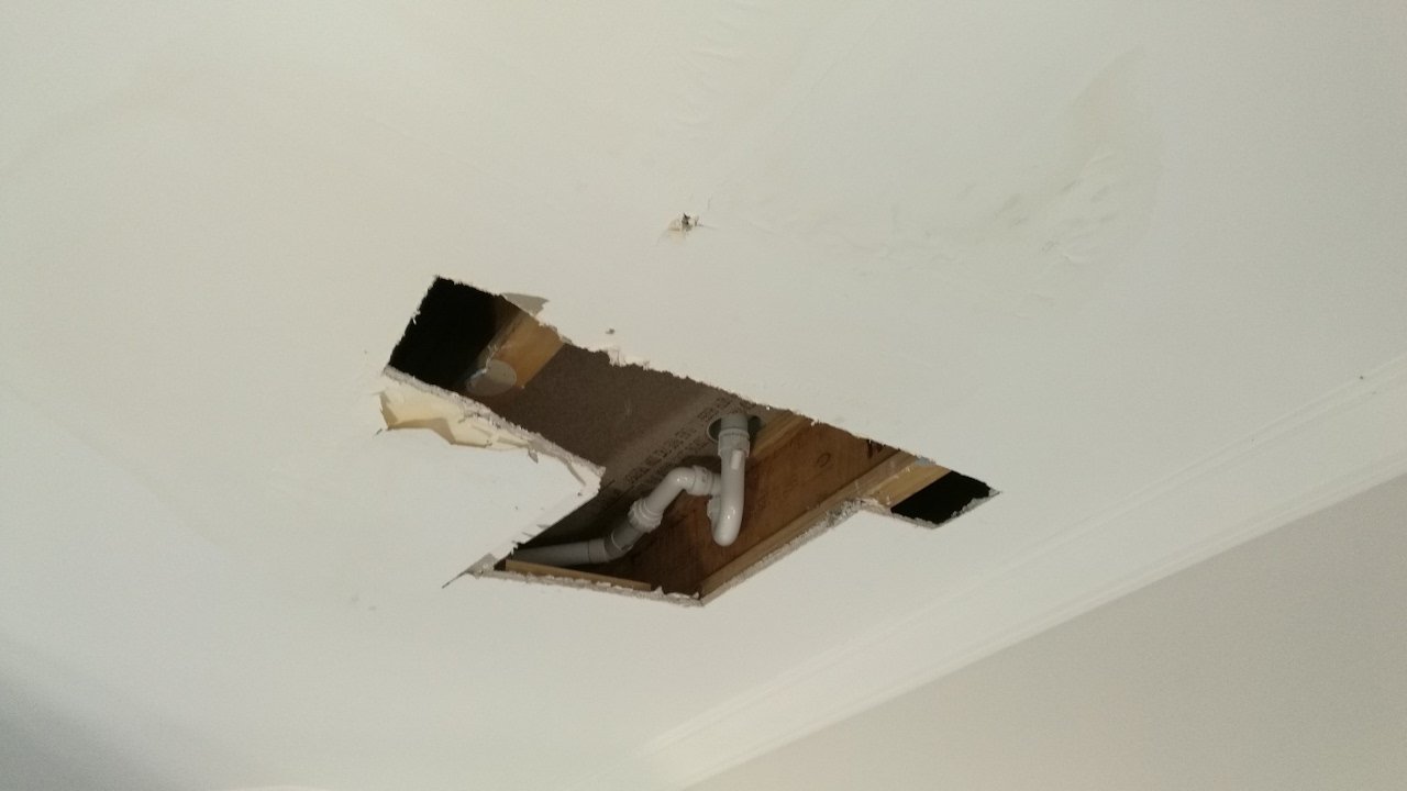 Ceiling water damage repair showing technician fixing leaking and stained ceiling